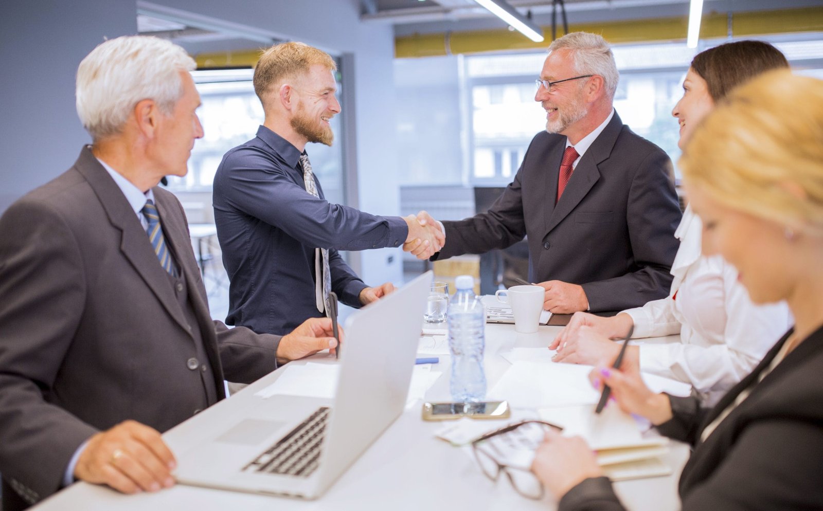 Care providers shaking hands across a meeting table